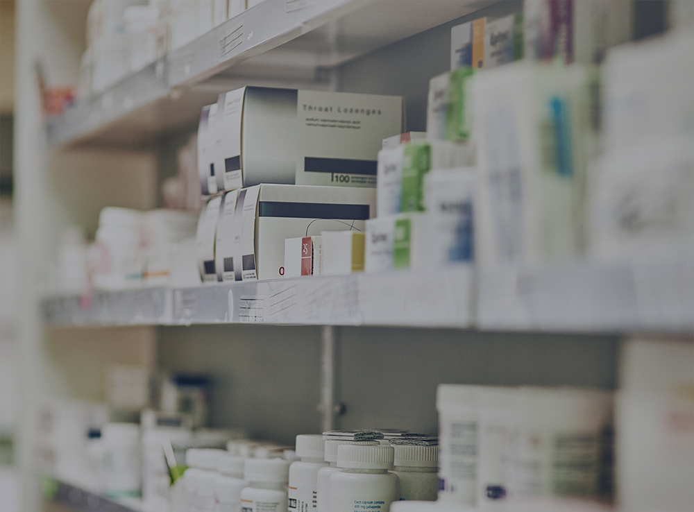 Closeup, pharmacy and medicine with healthcare, pills and shelf with boxes, bottles and treatment. Zoom, medication and package with container, retail and store with pharmaceutical, items or products